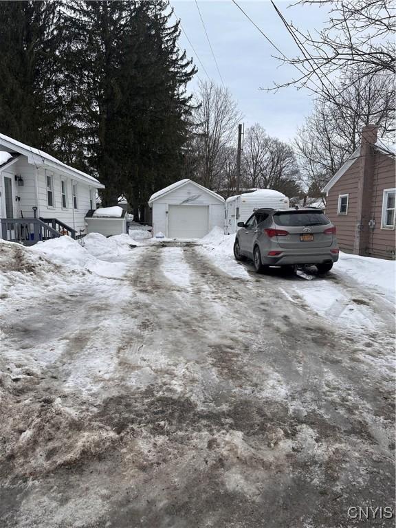 yard layered in snow featuring a garage and an outdoor structure