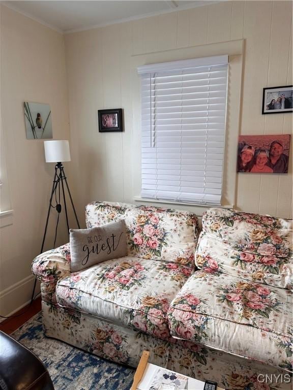 living area with baseboards, wood finished floors, and crown molding