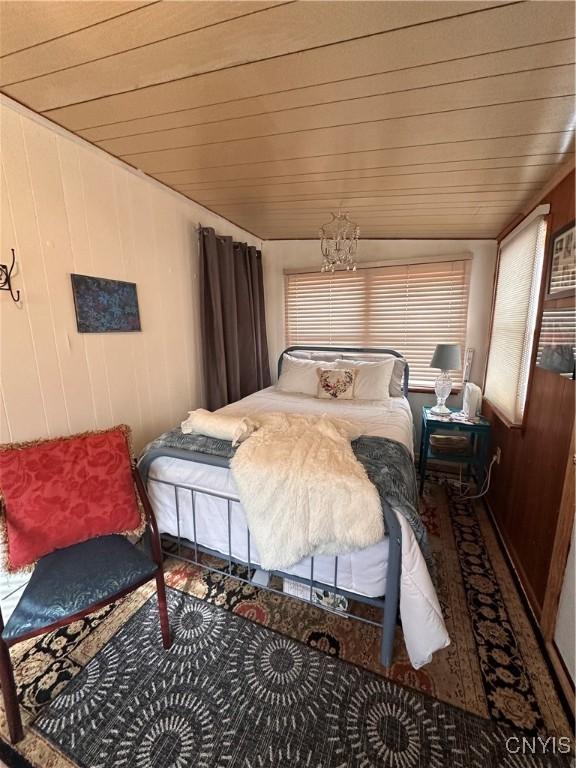 bedroom featuring wooden ceiling and wood walls