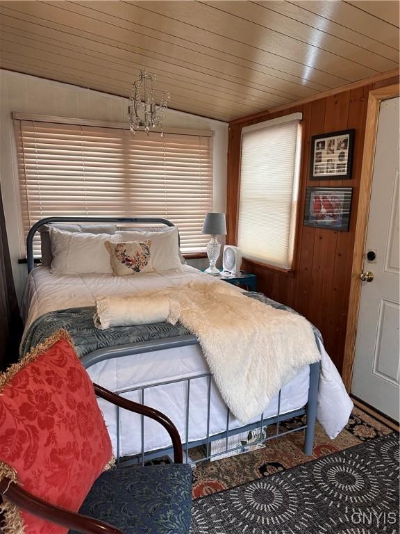 bedroom with a chandelier, wooden ceiling, and wood walls