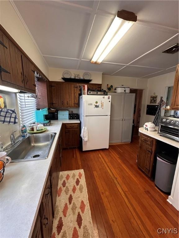 kitchen featuring dark wood-style floors, a toaster, light countertops, freestanding refrigerator, and a sink