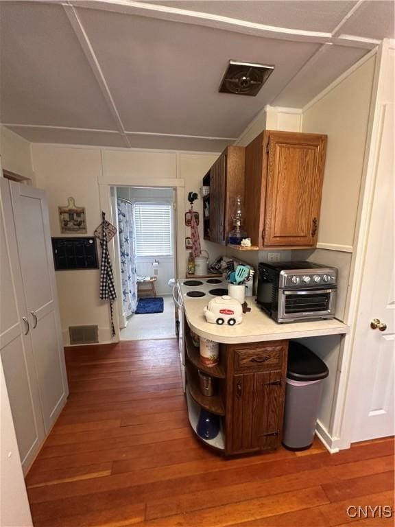 kitchen featuring light wood finished floors, a toaster, brown cabinetry, light countertops, and open shelves