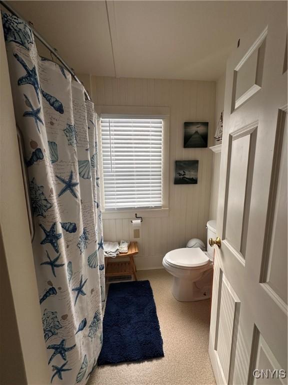 bathroom with a shower with shower curtain and toilet