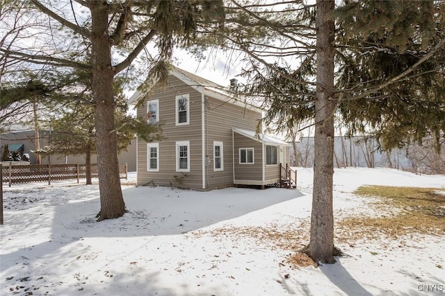 snow covered rear of property featuring fence