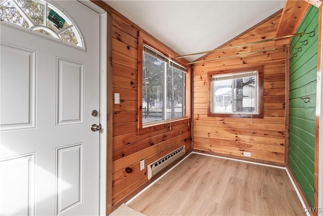 doorway with a baseboard heating unit, light wood-type flooring, vaulted ceiling, and wooden walls