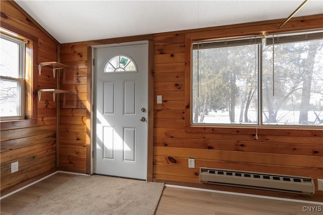 foyer featuring wooden walls, a baseboard radiator, lofted ceiling, and wood finished floors