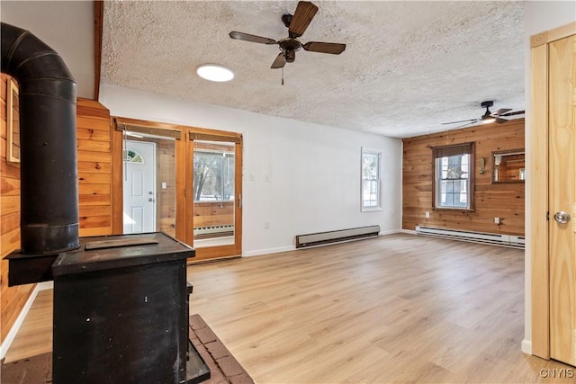 unfurnished living room featuring a baseboard radiator, a wood stove, and wooden walls