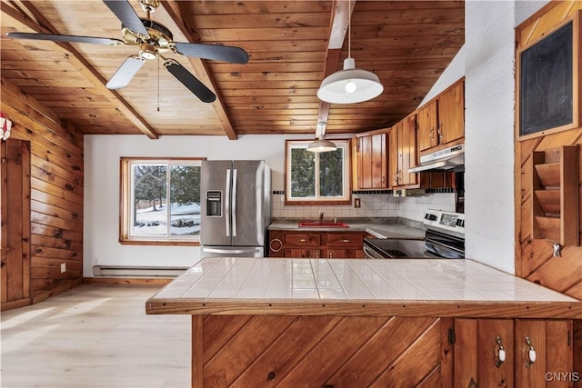 kitchen with a baseboard heating unit, stainless steel appliances, tile counters, and under cabinet range hood