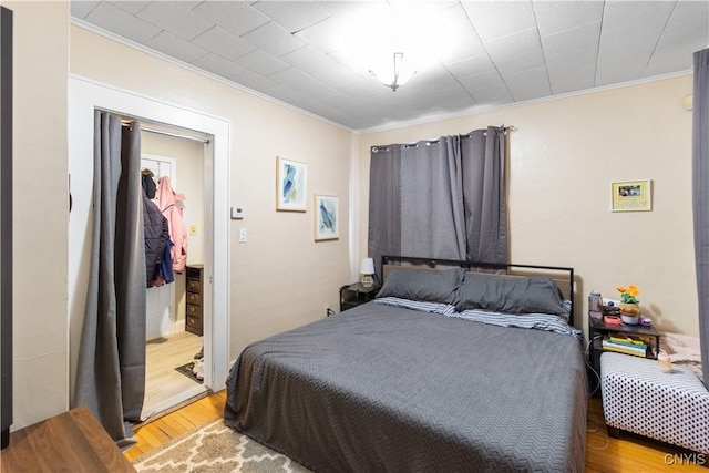 bedroom with light wood-type flooring and crown molding