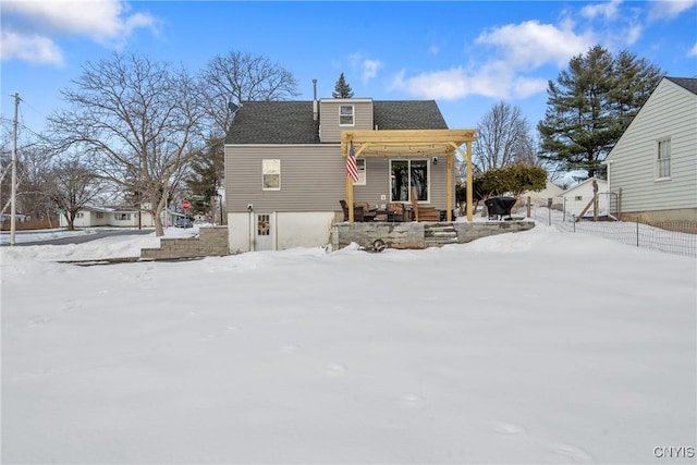 snow covered rear of property featuring fence and a pergola