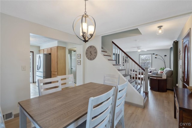 dining space with light wood-type flooring, visible vents, stairway, and a ceiling fan