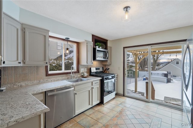 kitchen with a textured ceiling, stainless steel appliances, backsplash, and a sink