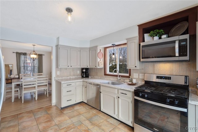 kitchen with decorative light fixtures, stainless steel appliances, decorative backsplash, an inviting chandelier, and a sink