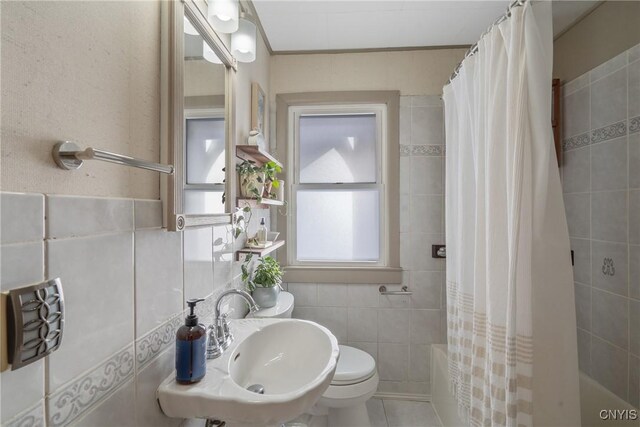 bathroom featuring tiled shower / bath, tile walls, toilet, a sink, and tile patterned flooring