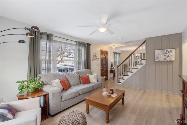 living room featuring stairs, a ceiling fan, and light wood-style floors