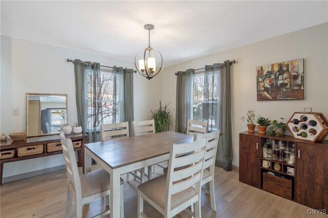 dining space with a healthy amount of sunlight, an inviting chandelier, and light wood-style floors