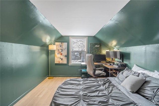 bedroom with vaulted ceiling and wood finished floors