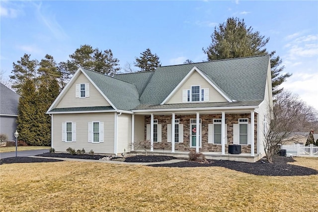 view of front of house with covered porch, a shingled roof, fence, and a front lawn