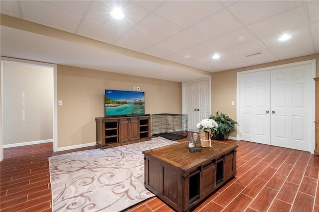 living room with wood finish floors, a drop ceiling, baseboards, and recessed lighting