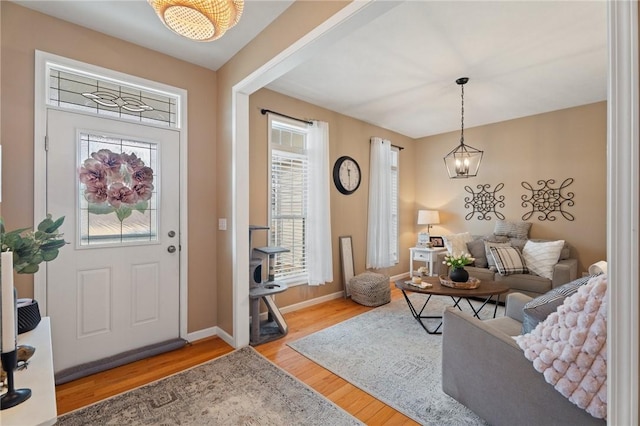 foyer entrance with a notable chandelier, baseboards, and wood finished floors