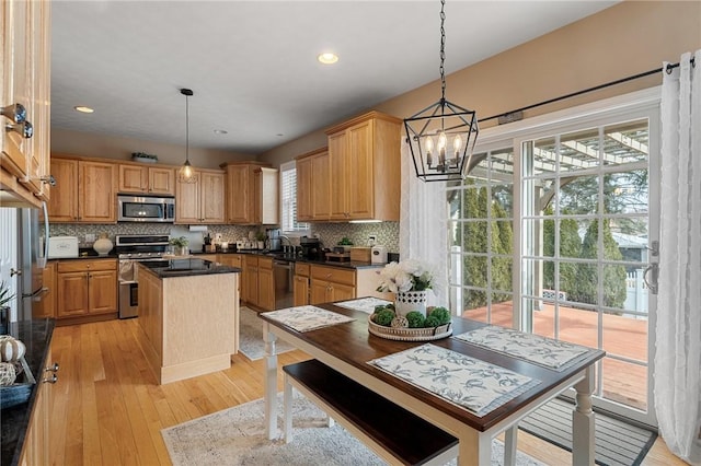 kitchen with tasteful backsplash, light wood-style flooring, a center island, stainless steel appliances, and a chandelier