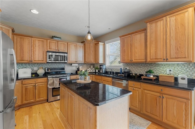 kitchen with tasteful backsplash, a kitchen island, appliances with stainless steel finishes, light wood-style floors, and pendant lighting