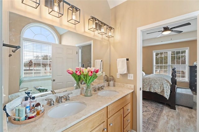 ensuite bathroom with a ceiling fan, a sink, ensuite bath, and double vanity