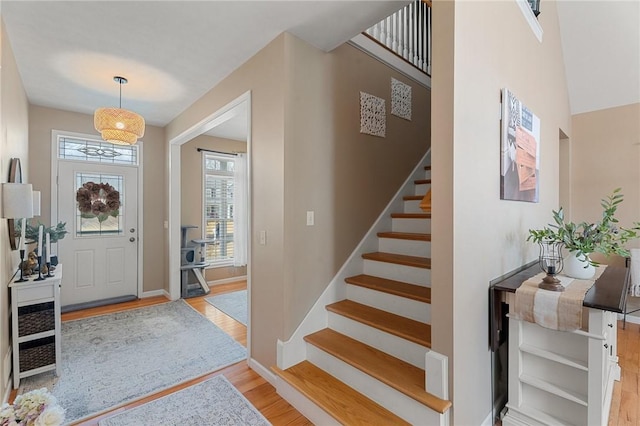 foyer featuring baseboards, stairway, and light wood-style floors