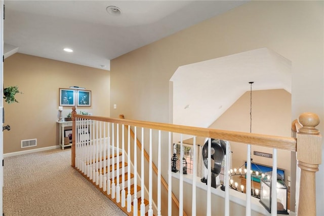 hall with lofted ceiling, carpet flooring, an upstairs landing, visible vents, and baseboards