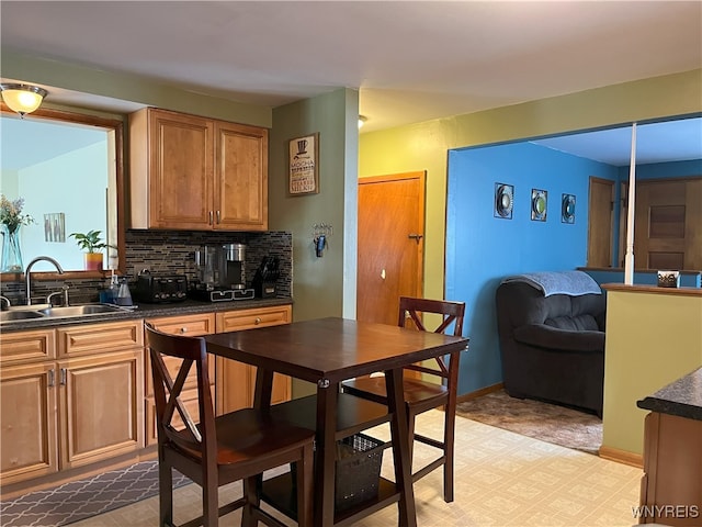 kitchen featuring baseboards, dark countertops, a sink, and decorative backsplash