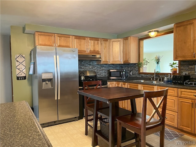 kitchen with under cabinet range hood, stainless steel appliances, a sink, decorative backsplash, and light floors