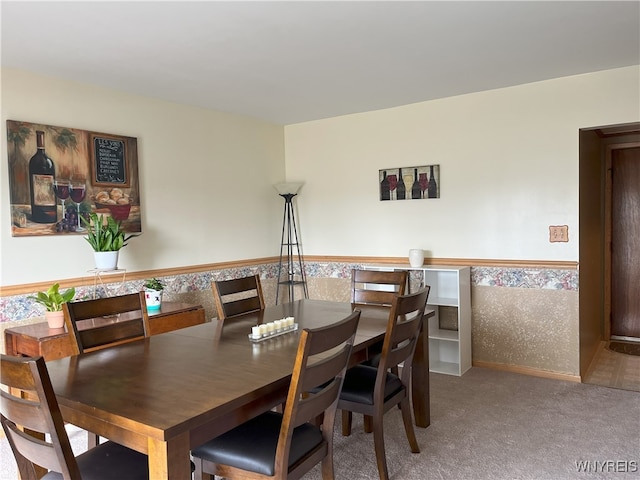 carpeted dining area featuring wainscoting