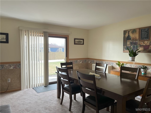 carpeted dining area featuring a wainscoted wall