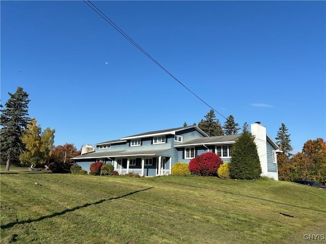 view of front of property with a chimney, a porch, and a front yard