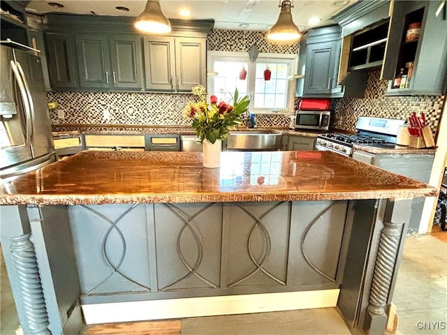 kitchen with a breakfast bar, hanging light fixtures, decorative backsplash, appliances with stainless steel finishes, and a kitchen island