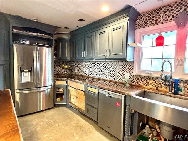 kitchen with decorative backsplash, dark countertops, appliances with stainless steel finishes, decorative light fixtures, and a sink