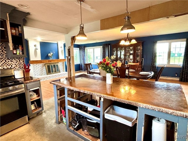 kitchen with decorative backsplash, decorative light fixtures, an inviting chandelier, concrete flooring, and gas stove