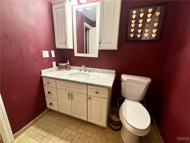 bathroom with toilet, tile patterned flooring, baseboards, and vanity