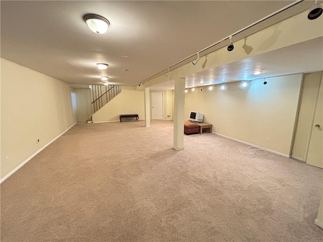 finished basement featuring carpet, baseboards, track lighting, and stairs