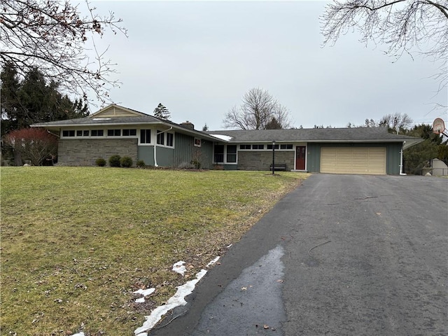 single story home with an attached garage, driveway, stone siding, a chimney, and a front yard