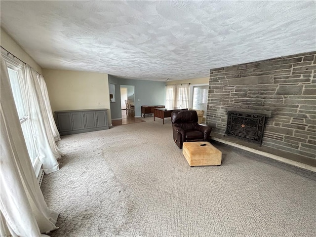 carpeted living room featuring a textured ceiling and a fireplace