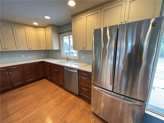 kitchen featuring stainless steel appliances, recessed lighting, light countertops, a sink, and light wood-type flooring