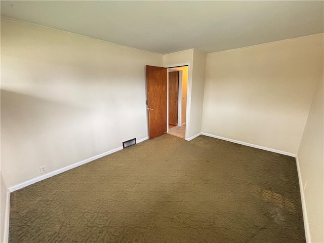 empty room with baseboards, visible vents, and dark carpet