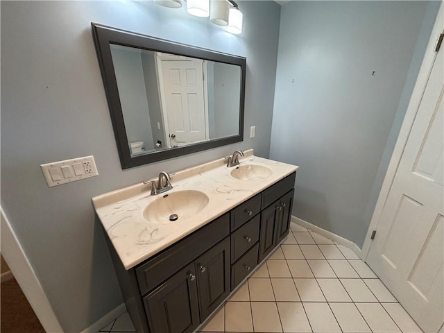 bathroom featuring double vanity, tile patterned flooring, baseboards, and a sink