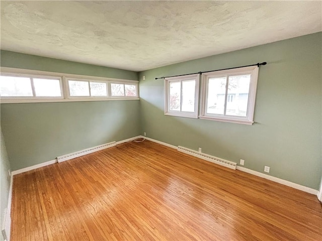 unfurnished room with a baseboard radiator, baseboards, and wood finished floors