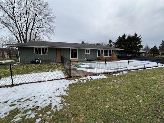 back of house featuring a fenced front yard, a fenced in pool, a lawn, and board and batten siding