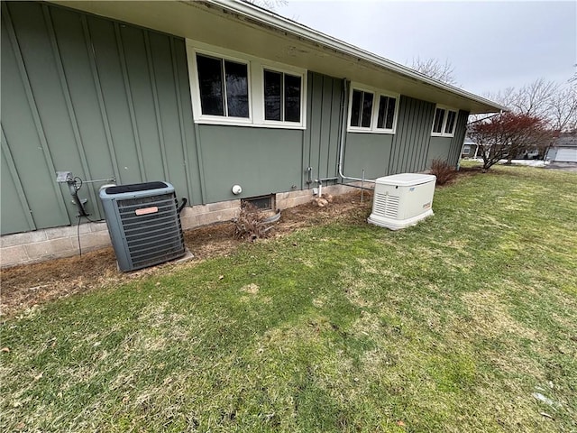 exterior space featuring crawl space, central AC unit, board and batten siding, and a lawn