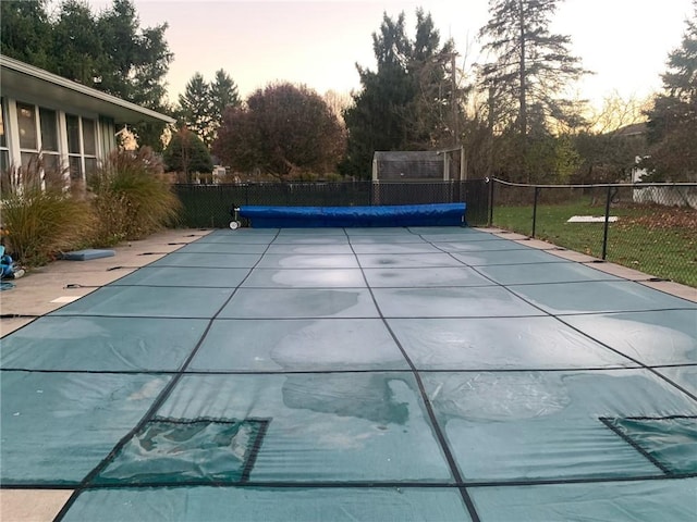 pool at dusk with a fenced in pool and fence