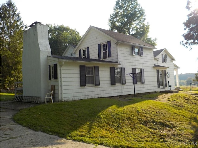 view of side of property featuring a chimney and a lawn