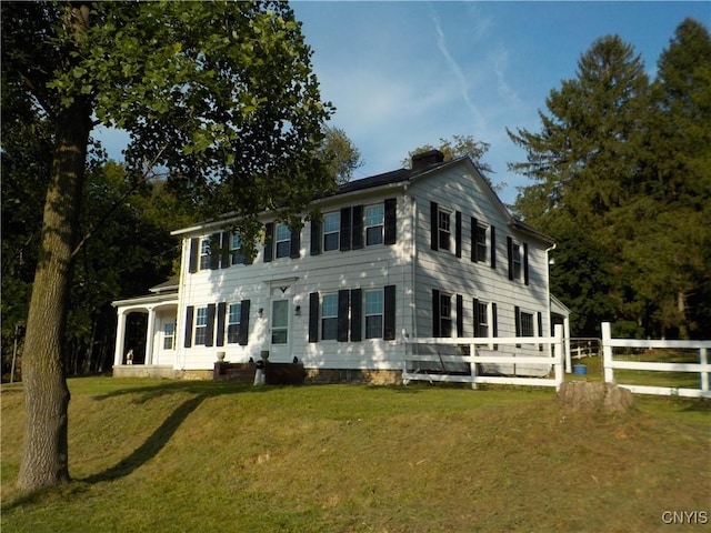 colonial inspired home with a front yard and fence